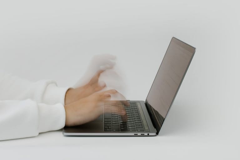 Hands rapidly typing on a laptop, illustrating speed and technology in a digital work environment.