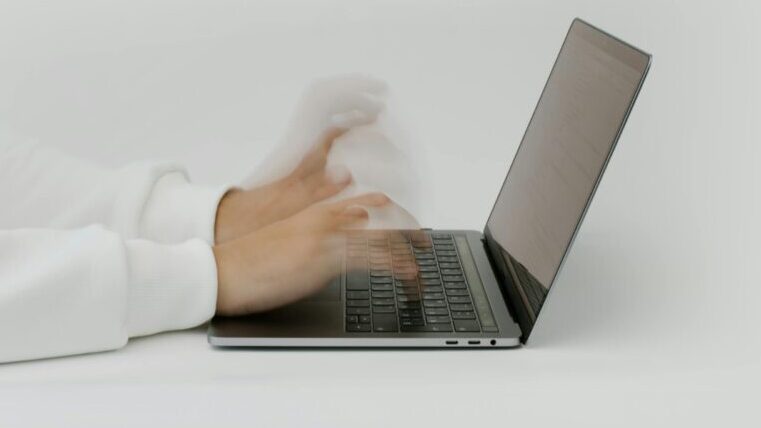 Hands rapidly typing on a laptop, illustrating speed and technology in a digital work environment.